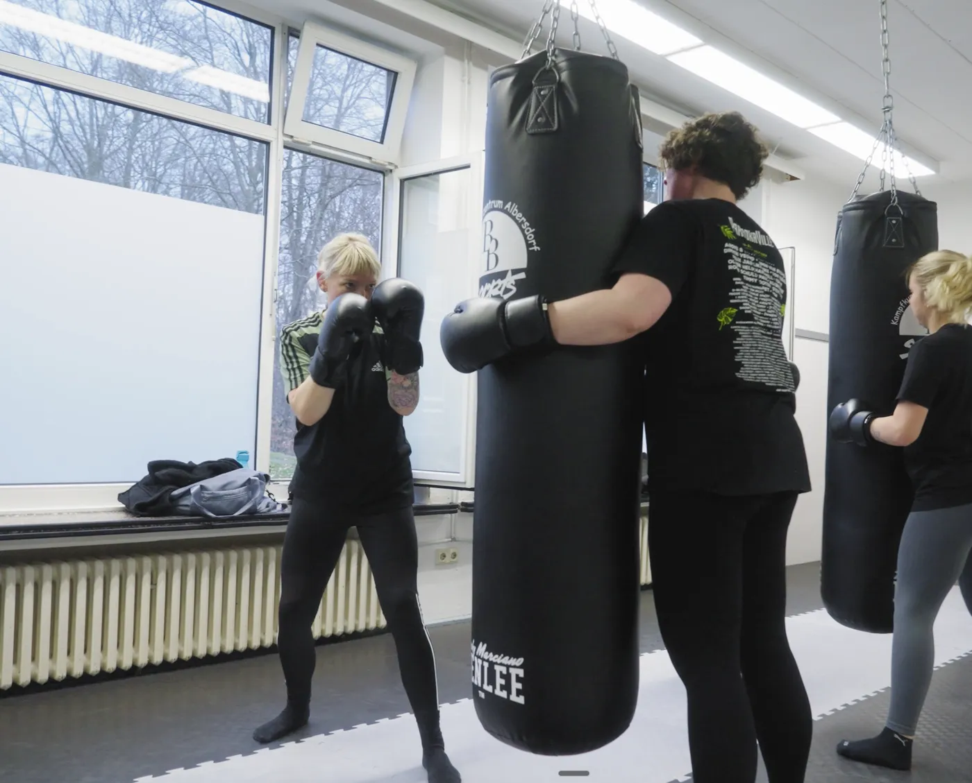 Teilnehmerin hält ihrer Partnerin den Sandsack beim Schlagtraining