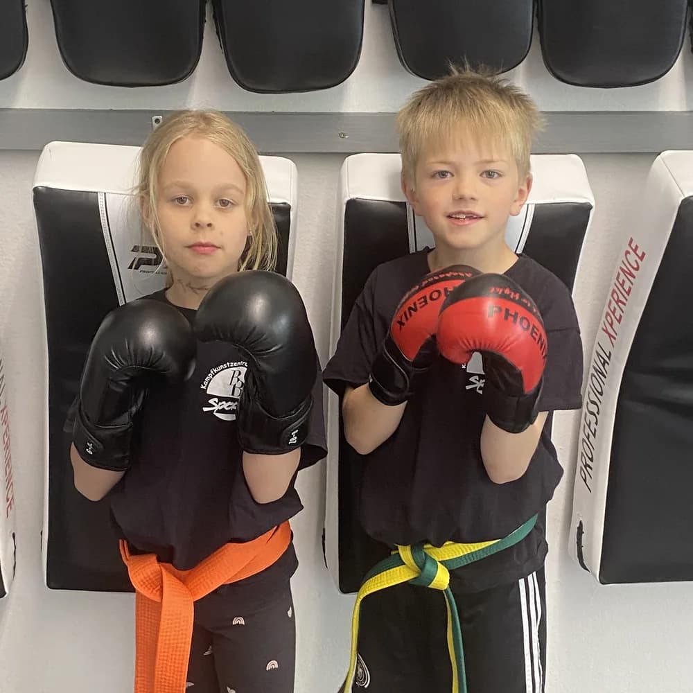 Mädchen und Junge mit Boxhandschuhen stehen bereit fürs Training