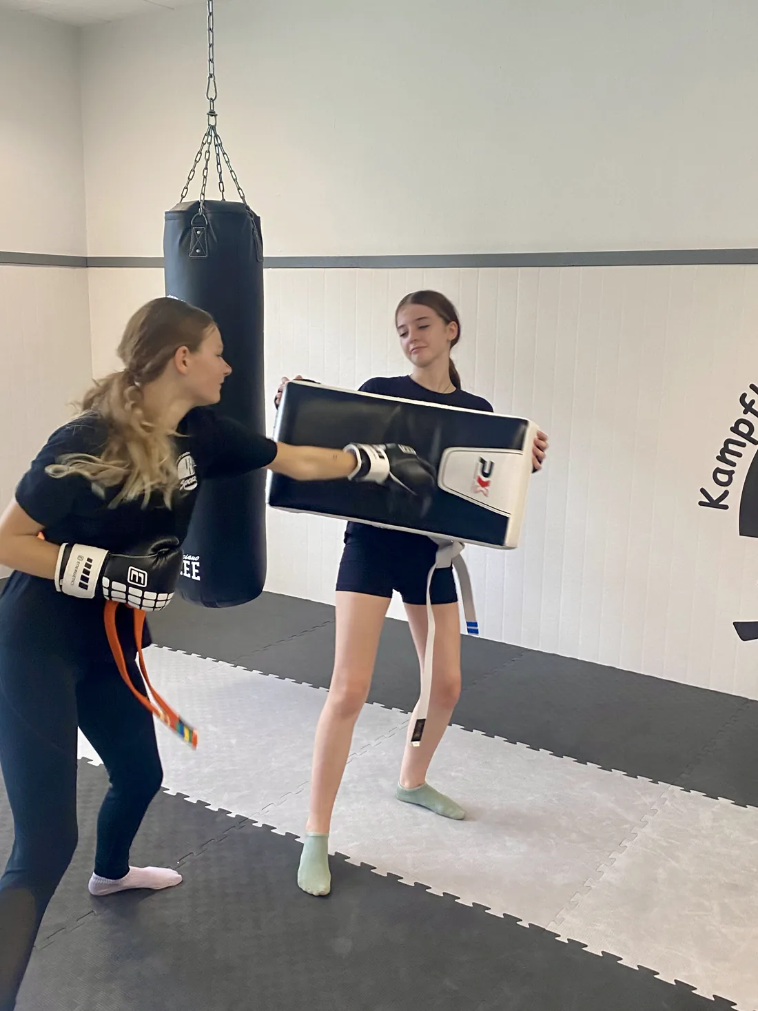 Jugendliche kickt gegen das Schlagpolster ihrer Trainingspartnerin