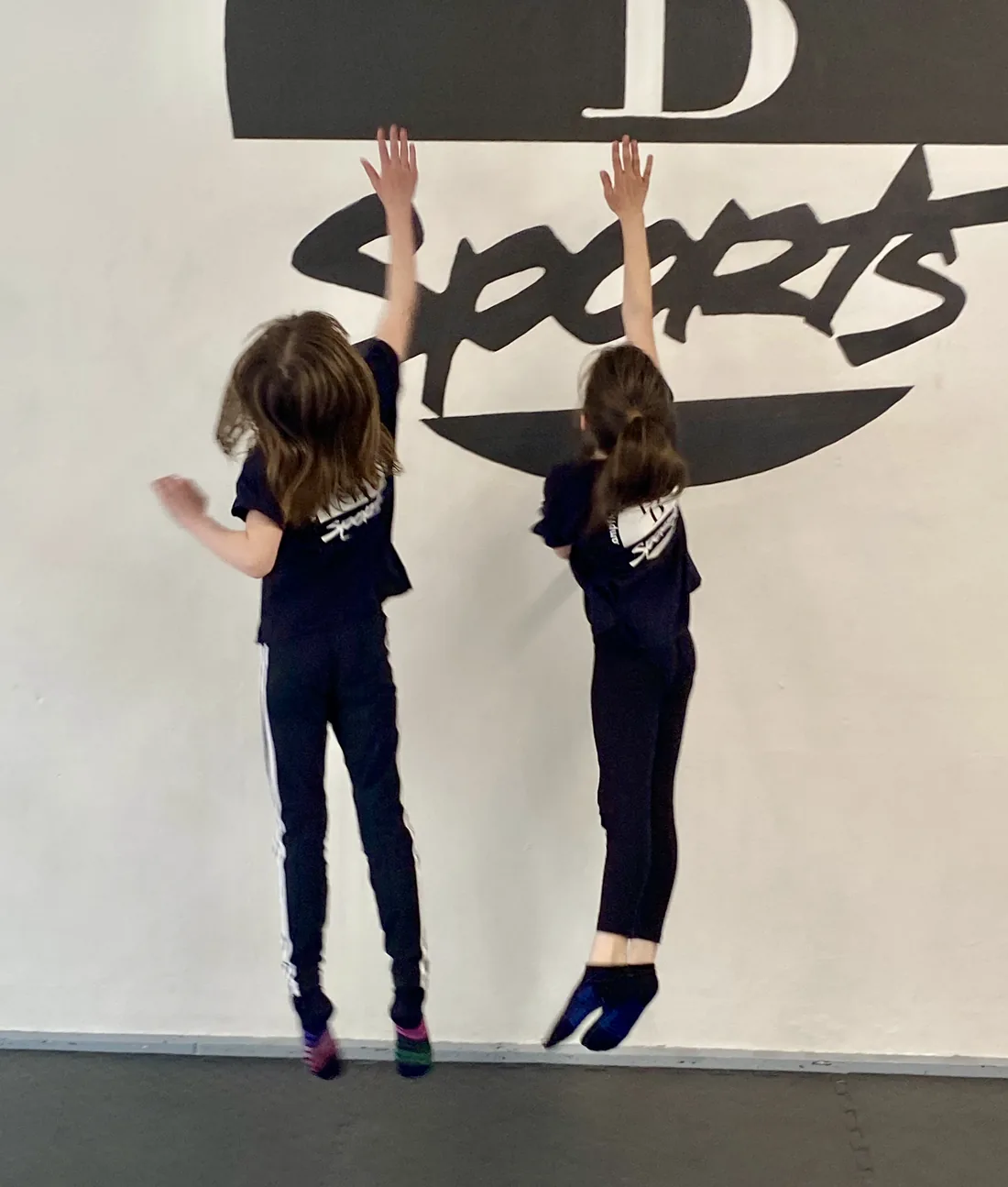 Zwei Jugendliche springen bei einer Konditionsübung an der Wand ab