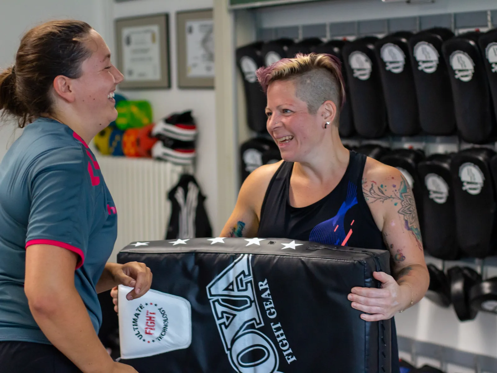 Zwei Erwachsene lachen gemeinsam beim Krav-Maga-Training
