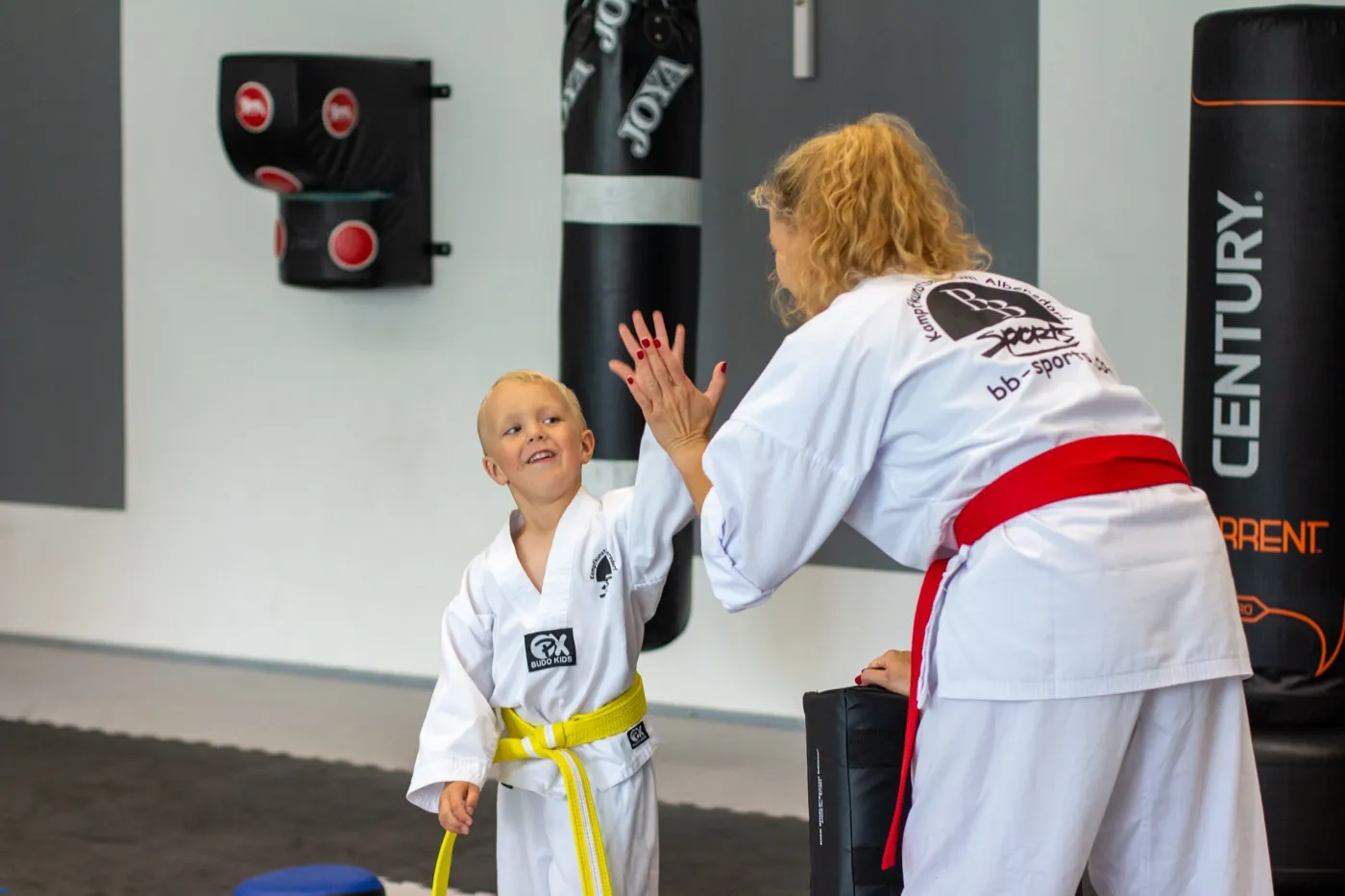 Trainerin gibt einem Kind im Kampfsportanzug ein High-Five